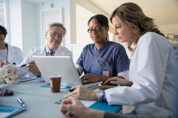 Several doctors seated around a laptop.